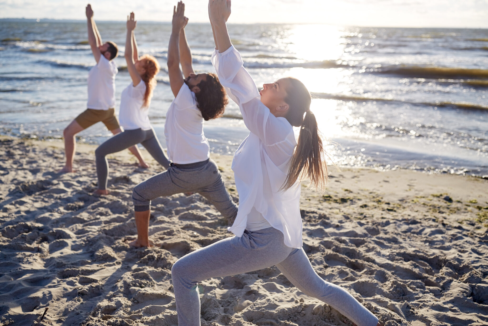 Group Of People Making Yoga Exercises On Beach